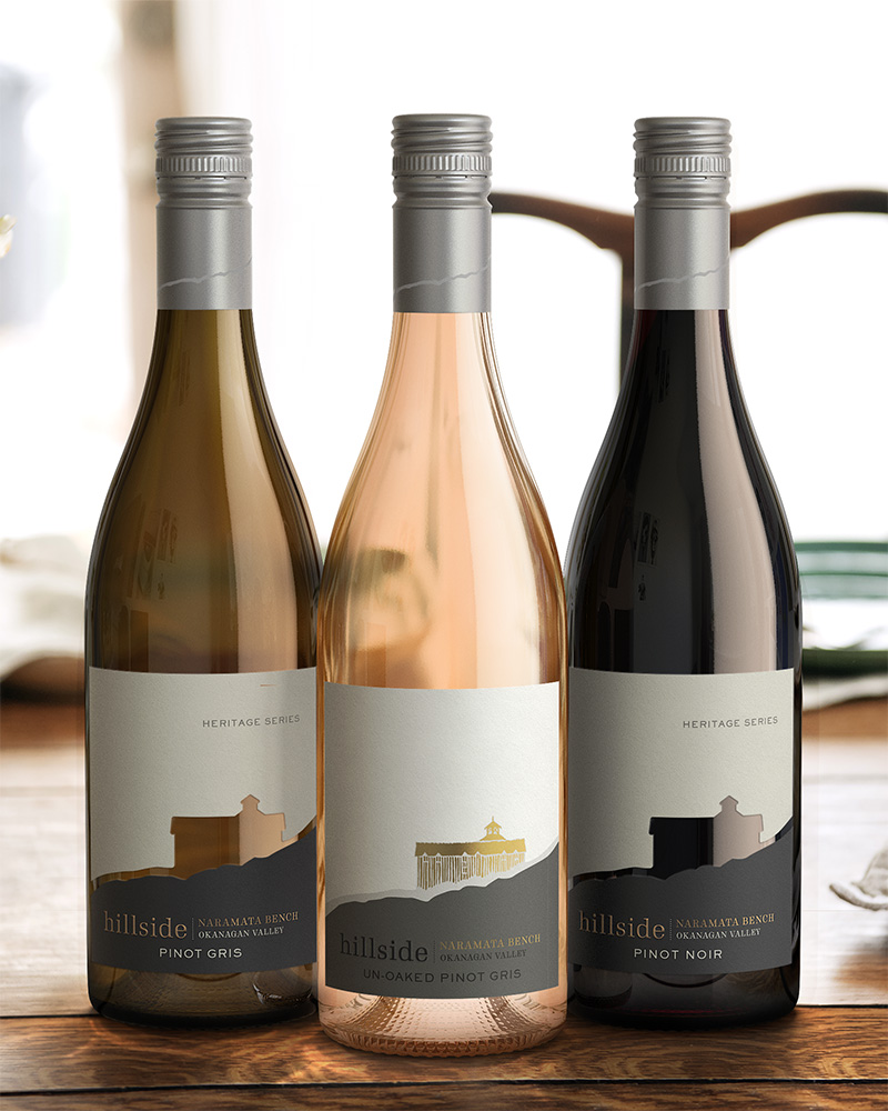Three Hillside Winery wine bottles placed in a triangle on a wood table. The left bottle being a Pinot Gris, the centred bottle an Un-Oaked Pinot Gris, and the right bottle being a Pinot Noir. 